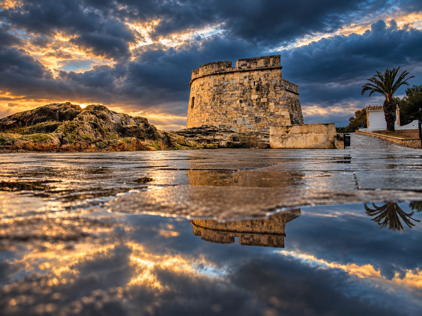 Castillo de Moraira al atardecer reflejado en el paseo junto al mar