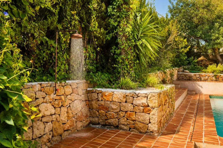 Jardín mediterráneo con muro de piedra junto a la piscina en Dénia